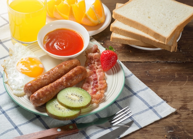 Nutritious breakfast, biscuits, strawberries, coffee, sausages, orange juice on the table