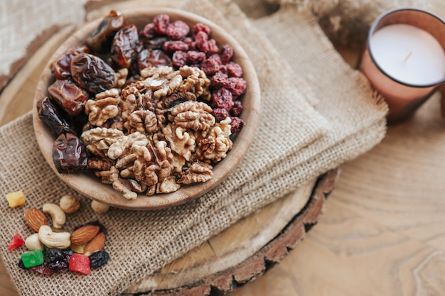 Nuts dates and cranberries in a wooden plate top view