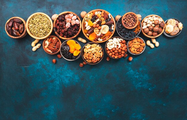 Nuts and dried fruits in assortment Dry apricots figs raisins walnuts almonds and other Blue table background top view copy space