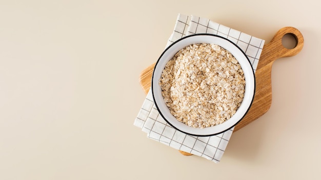 Oat flakes in a bowl on a napkin on a beige background Copy space