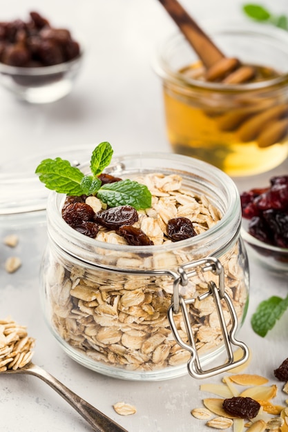 Oat flakes in glass jar with honey, raisins and nuts. Healthy breakfast concept.