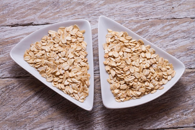 Oat flakes in white bowl on wooden table