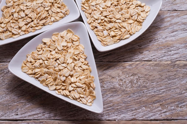 Oat flakes in white bowl on wooden table