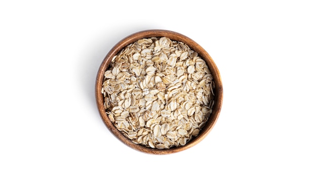 Oat flakes in wooden plate isolated on white