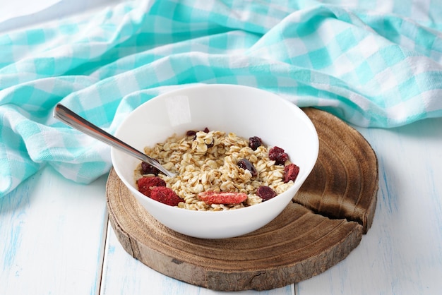 Oat grain cereal with berries and honey in a white plate on a wooden table.