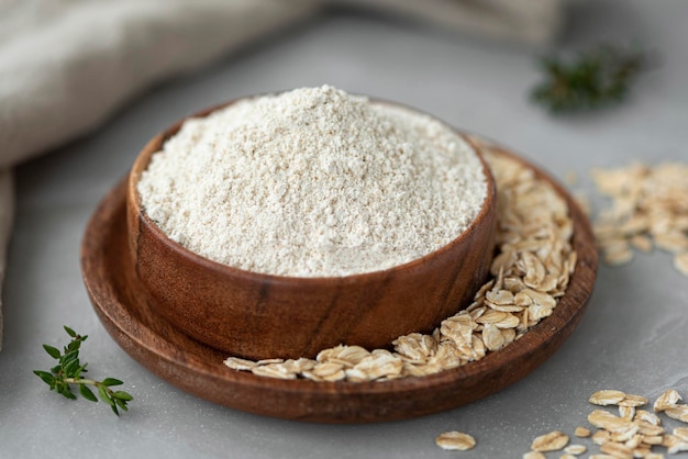 Oat wholegrain flour with oat flakes on wooden table