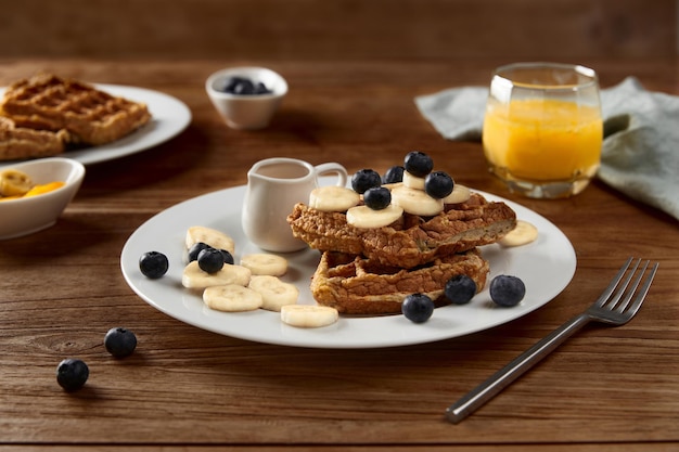 Oatmeal belgian waffles topped with banana and blueberry on rustic wooden table