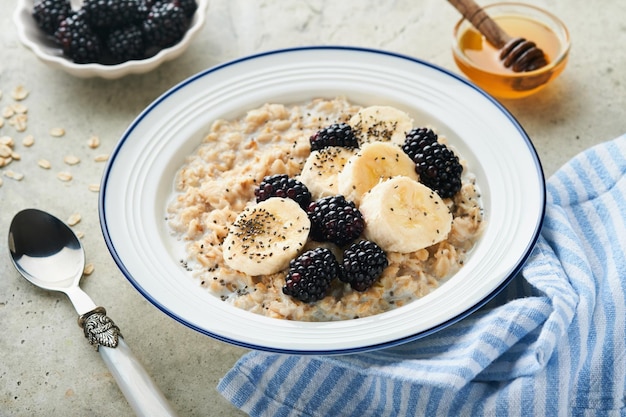 Oatmeal Bowl of oatmeal porridge with blackberry bananas and chia seeds on gray concrete old table background Top view in flat lay style Natural ingredients Hot and healthy breakfast and diet food