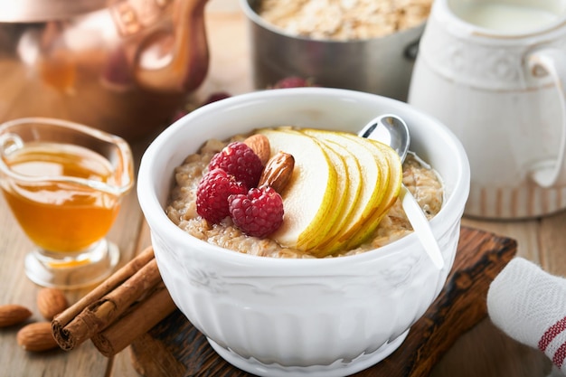 Oatmeal Bowl of oatmeal porridge with raspberry pear and honey on old wooden table background Hot and healthy food for Breakfast top view flat lay