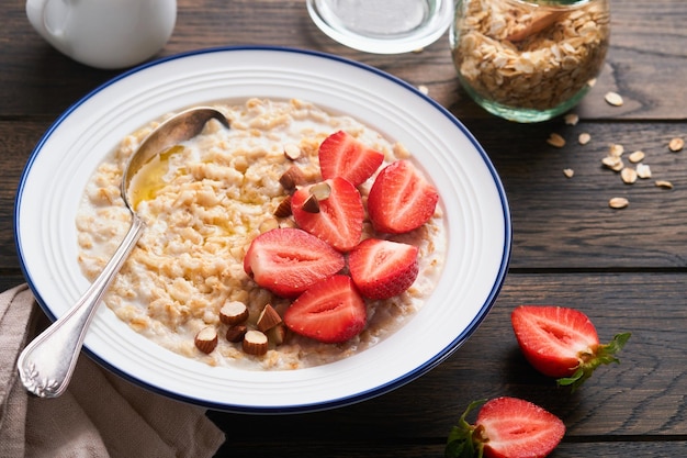 Oatmeal Bowl of oatmeal porridge with strawberry almond and milk on old wooden dark table background Top view in flat lay style Natural ingredients Hot and healthy breakfast and diet food