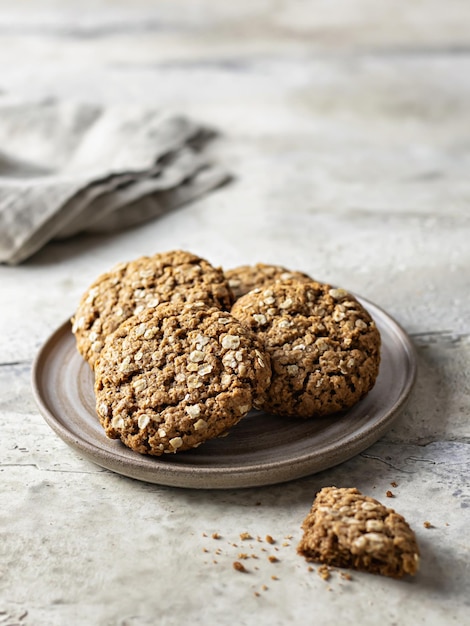 Oatmeal cookies on ceramic plate on textured background. Still life. Vertical orientation