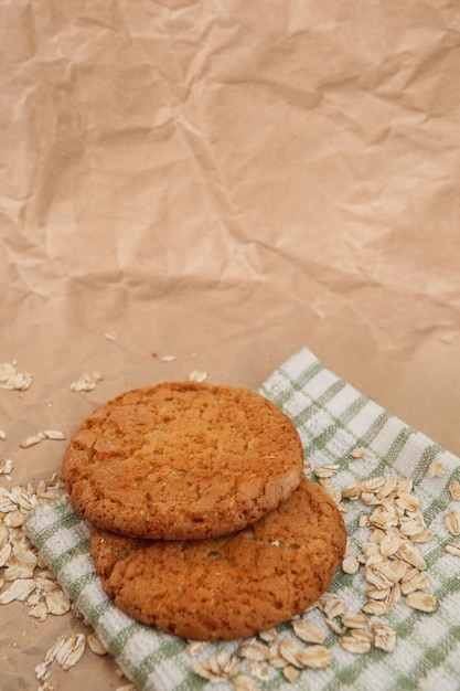 Oatmeal cookies and scattered oatmeal on crumpled paper background