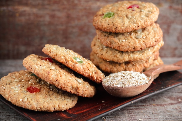 Oatmeal cookies and a spoon with oat flakes on a wooden table