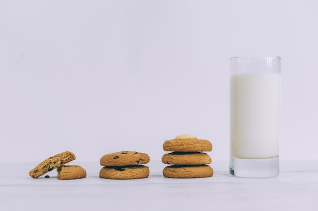 Oatmeal cookies with chocolate on a light background with a glass of milk