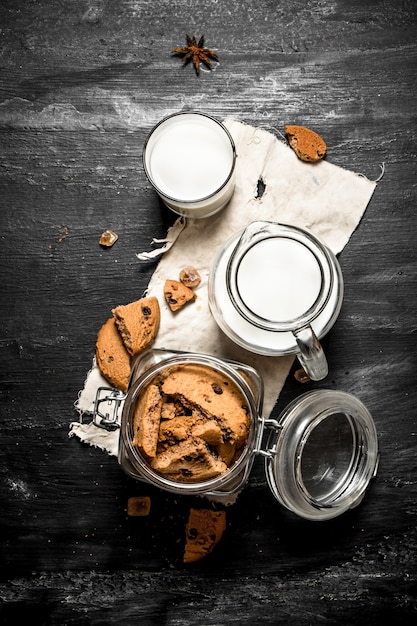 Oatmeal cookies with fresh milk. On a black wooden table.