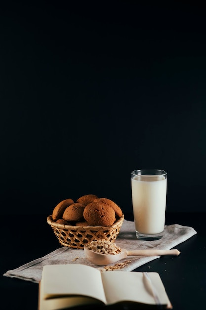 Oatmeal cookies with a glass of milk on a napkin on a black background The concept of a healthy breakfast