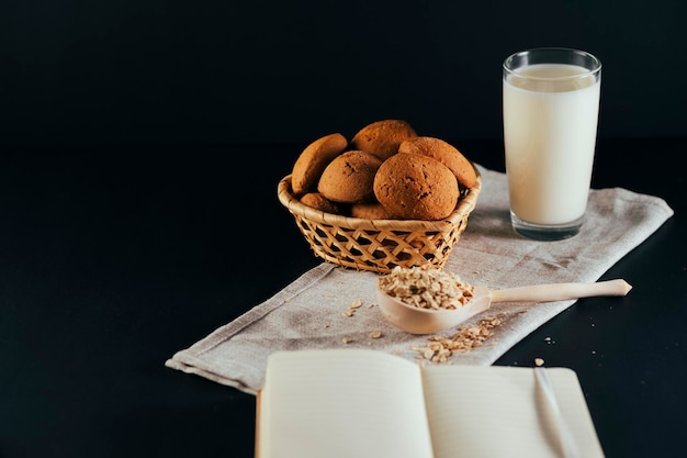 Oatmeal cookies with a glass of milk on a napkin on a black background The concept of a healthy breakfast