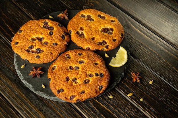 Oatmeal cookies with raisins spices and lemon on a black serving board prepared for breakfast