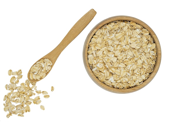 oatmeal flakes in wooden bowl and spoon isolated on white