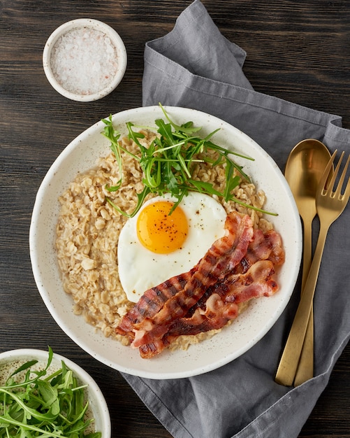 Oatmeal, fried egg and fried bacon.