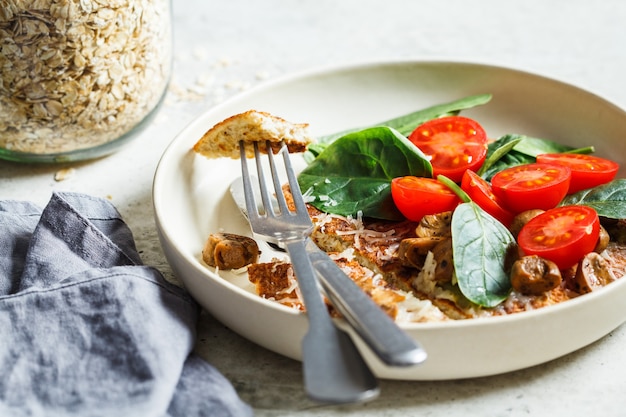 Oatmeal omelet pancake with cheese, mushrooms, tomatoes and spinach. Healthy fitness breakfast.