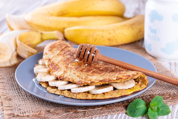 Oatmeal pancakes with banana and honey on plate