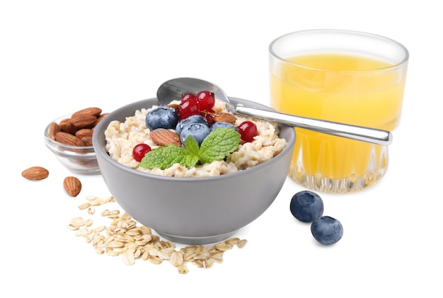 Oatmeal served with berries almonds and honey on white background