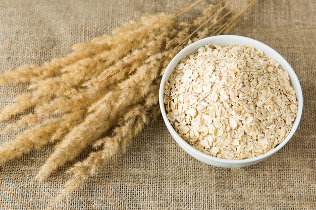 Oatmeal in white bowl with spikes on textile background. Healthy eating