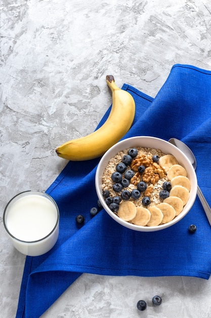 Oatmeal with bananas, blueberries and walnut and glass  of milk for healthy breakfast