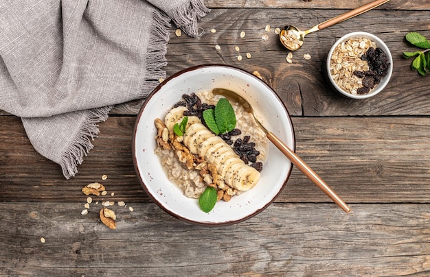 Oatmeal with dried raisins banana and walnuts decorated with mint Healthy diet vegetarian breakfast or snack Clean eating dieting vegan food concept top view