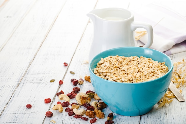 Oatmeal with nuts and dried fruits on old white painted wooden table