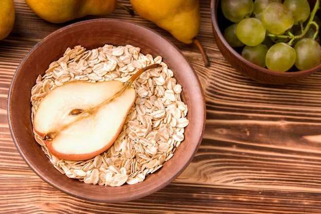 Oatmeal with pear in a bowl near grapes