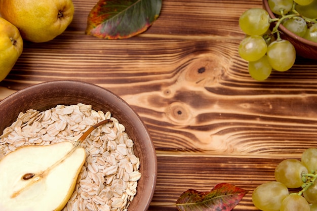 Oatmeal with pear in a bowl near grapes