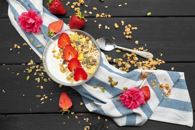 Oatmeal with yogurt and berries on a black wooden background. Top view. Healthy breakfast.