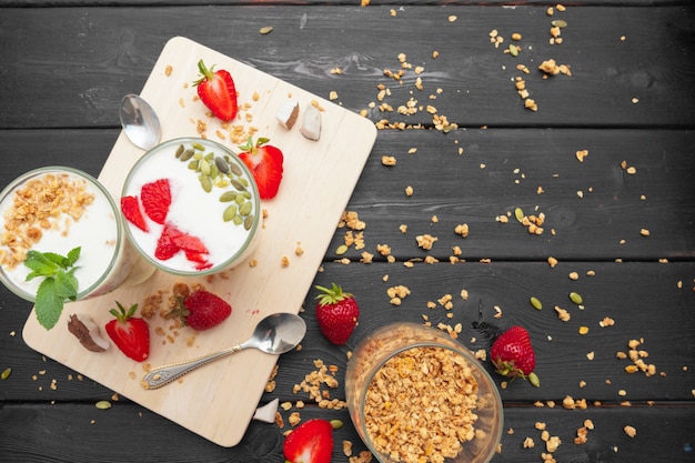 Oatmeal with yogurt and berries on a black wooden background.