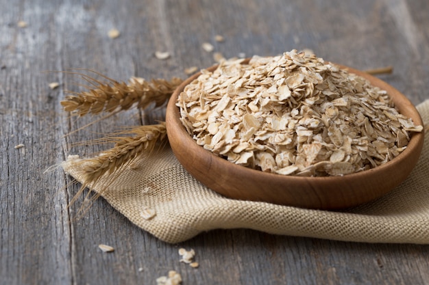 Oats, oat flakes, rolled oats in wooden bowl. Concept of healthy eating, dieting, healthy lifestyle and weight loss