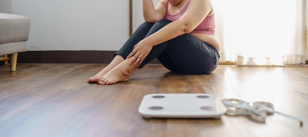 Obese Woman with fat upset bored of dieting Weight loss fail Fat diet and scale sad asian woman on weight scale at home weight control