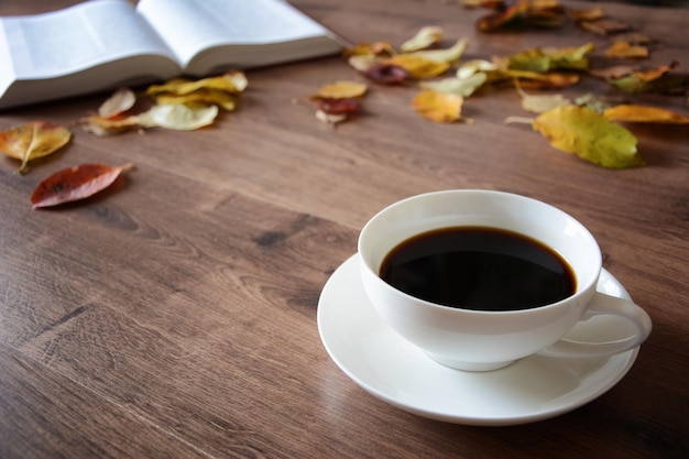 Objects on a wooden table a cup of coffee and a book