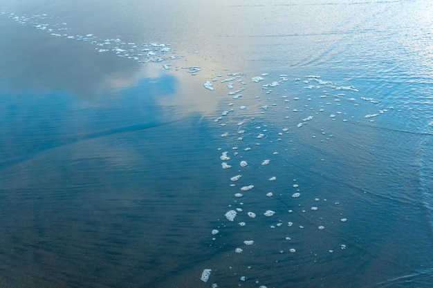 Ocean beach with a wave coming back in which the sky is reflected