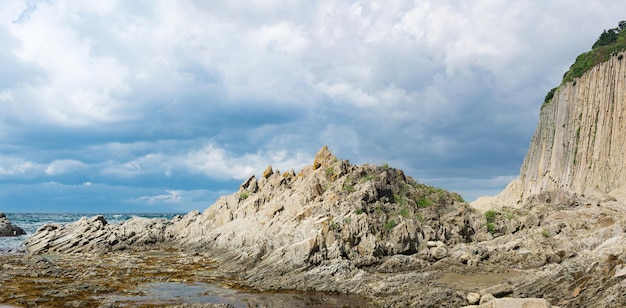 Ocean shore with rocks of columnar basalt Cape Stolbchaty on Kunashir Island