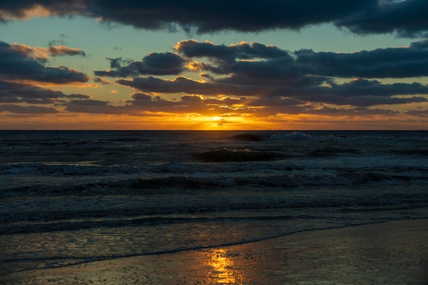 Ocean sunset landscape with soft evening sea water waves crushing on sandy beach