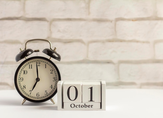 October 1 on a wooden calendar next to the alarm clock the date of the autumn month