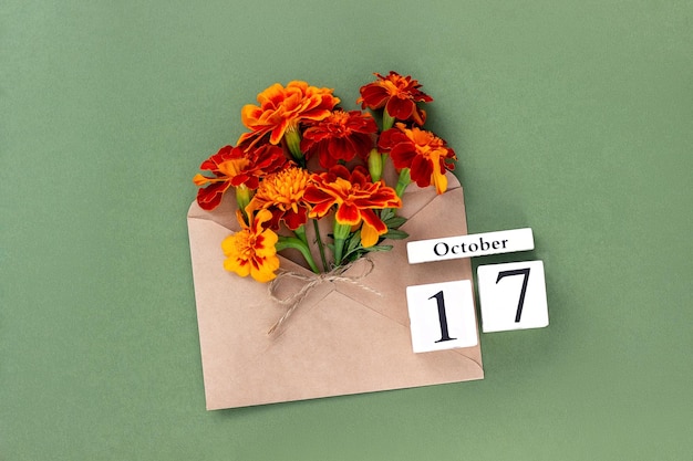 October 17 Bouquet of orange flower in craft envelope and calendar date on green background Minimal concept Hello fall Template for your design greeting card