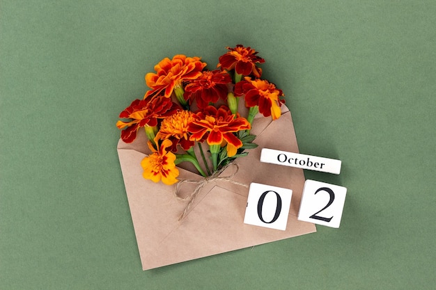 October 2 Bouquet of orange flower in craft envelope and calendar date on green background Minimal concept Hello fall Template for your design greeting card