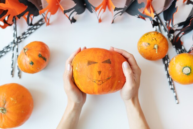 October 31. Halloween holiday. The girl holds the carved face of a pumpkin in her hands. View from above.