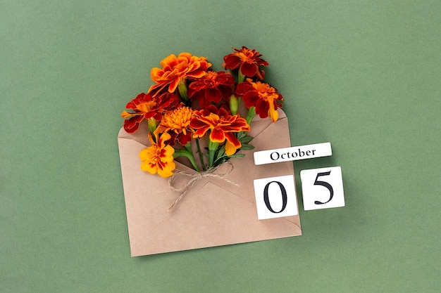 October 5 Bouquet of orange flower in craft envelope and calendar date on green background Minimal concept Hello fall Template for your design greeting card