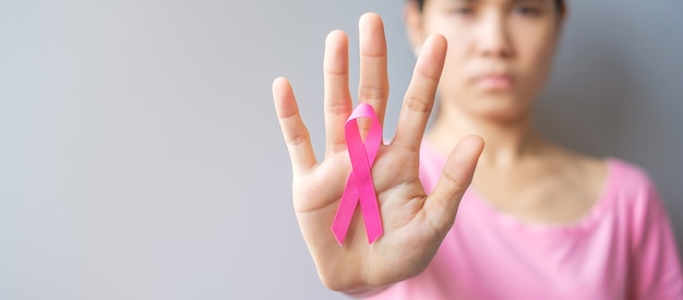 October Breast Cancer Awareness month, elderly Woman in pink T- shirt with hand holding Pink Ribbon for supporting people living and illness. International Women, Mother and World cancer day concept