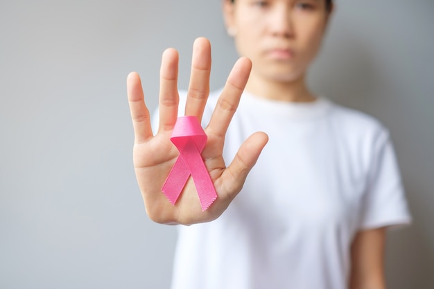 October Breast Cancer Awareness month, elderly Woman in white T- shirt with hand holding Pink Ribbon for supporting people living and illness. International Women, Mother and World cancer day concept