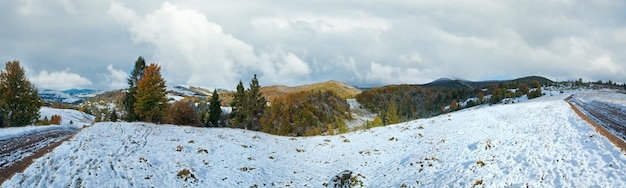 October Carpathian mountain panorama with first winter snow on dirty road