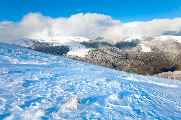 October mountain view with first winter snow and last autumn colourful foliage on far mountainside